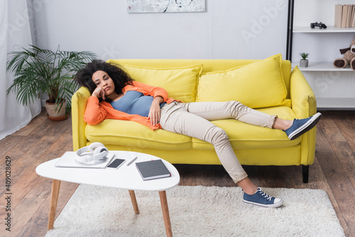 bored african american woman chilling on yellow couch