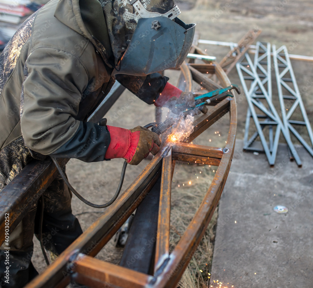 A worker welds metal for a canopy. A worker welds metal for a canopy.