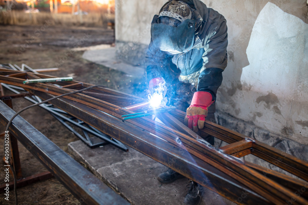 A worker welds metal for a canopy. A worker welds metal for a canopy.