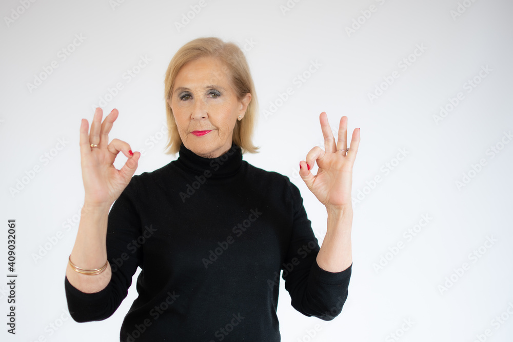 Senior beautiful blond woman wearing casual sweater over white background doing happy thumbs up gesture with hands. Approving expression looking at the camera showing success. Senior beautiful blond woman wearing casual sweater over white background doing happy thumbs up gesture with hands. Approving expression looking at the camera showing success.