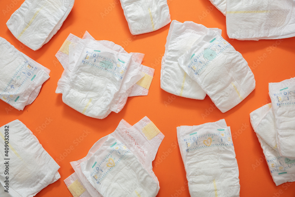Baby diapers collection on orange color background. - obrazy, fototapety, plakaty 