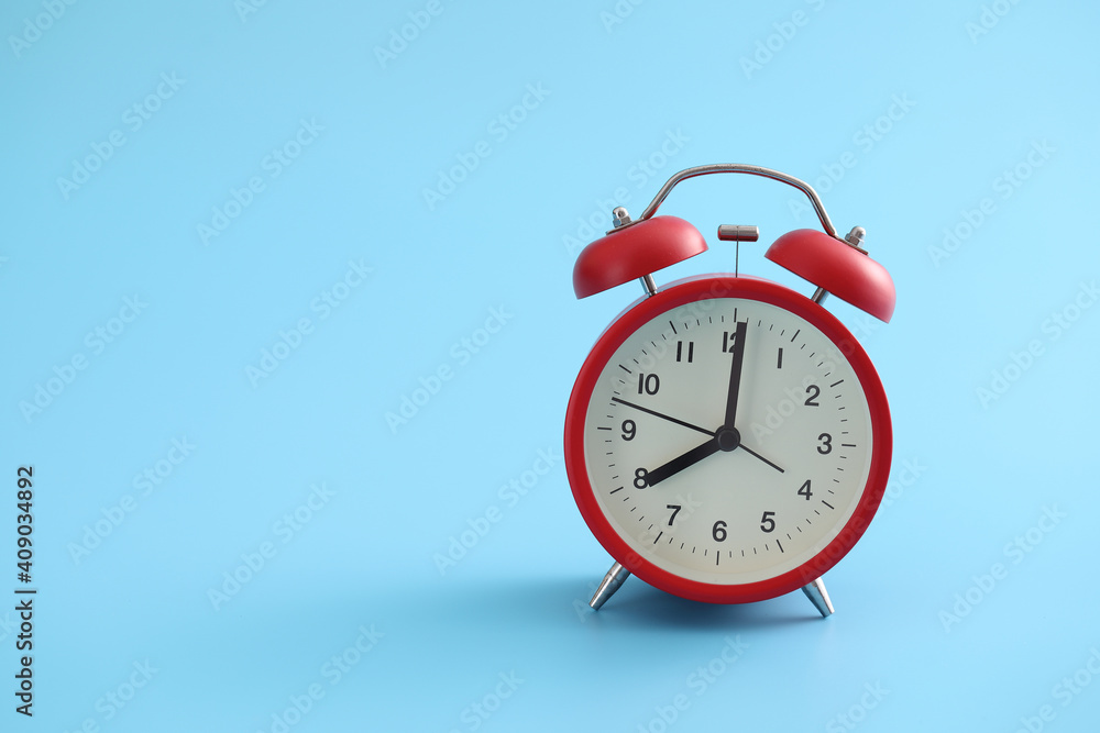 Red retro alarm clock isolated on a blue background Red retro alarm clock isolated on a blue background