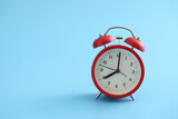 Red retro alarm clock isolated on a blue background
