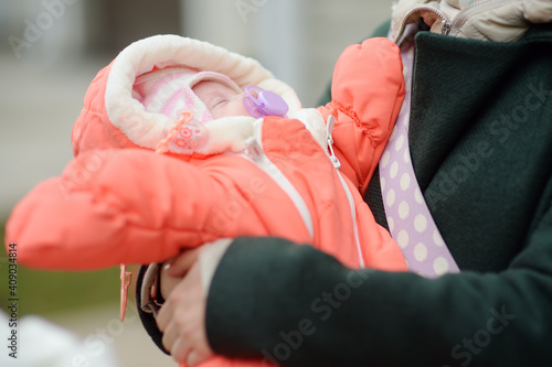 Newborn baby girl in her mother arms. Baby sleep quietly and sucks a pacifier