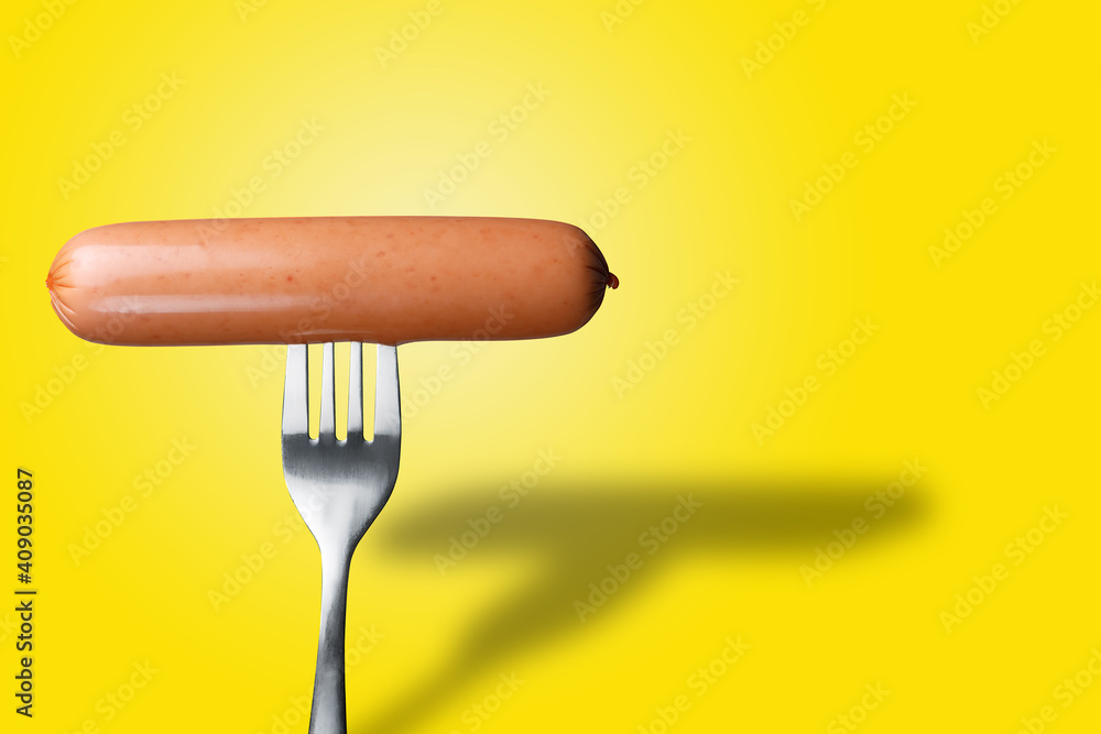 Sausage on a fork on a yellow isolated background. The concept of fast food. Copy space. Sausage on a fork on a yellow isolated background. The concept of fast food. Copy space.