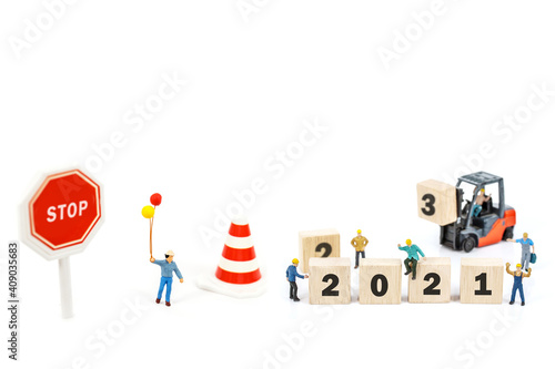 miniature worker team building standing front of forklift machine with white 2021 number on wooden block on white background.