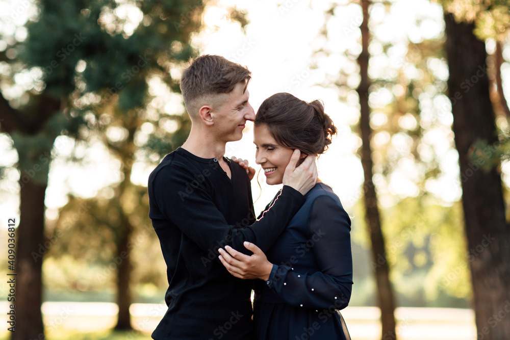 Cheerful young woman and man are hugging outdoor in summer park. Dating and romantic vacation. couple in love gently looking at each other on sunny day Cheerful young woman and man are hugging outdoor in summer park. Dating and romantic vacation. couple in love gently looking at each other on sunny day