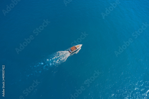 Drone view of a boat. Aerial view of a yacht on blue water. Top view of a white boat sailing in the blue sea. luxury motor boat.