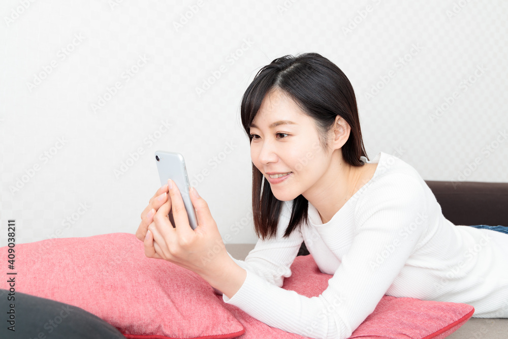 Woman lying on the couch and holding a smartphone Woman lying on the couch and holding a smartphone