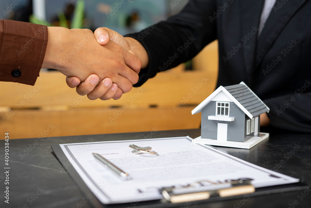 Real estate agents shaking hands To congratulate buyers after giving buyers a purchase contract, a contract idea. Trading houses and real estate