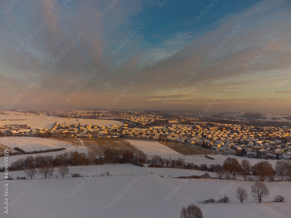 Aerial drone view of Lappersdorf and surrounding fields near Regensburg in Bavaria with snow during sunrise on clear cold winter day