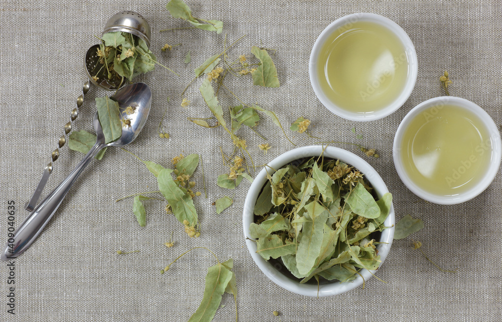 Dried lime-blossoms from above on linen textile with lime leaf flower buds neaby, overhead top view, flat lay, closeup, copy space, herbal tea nad naturopathy concept Dried lime-blossoms from above on linen textile with lime leaf flower buds neaby, overhead top view, flat lay, closeup, copy space, herbal tea nad naturopathy concept