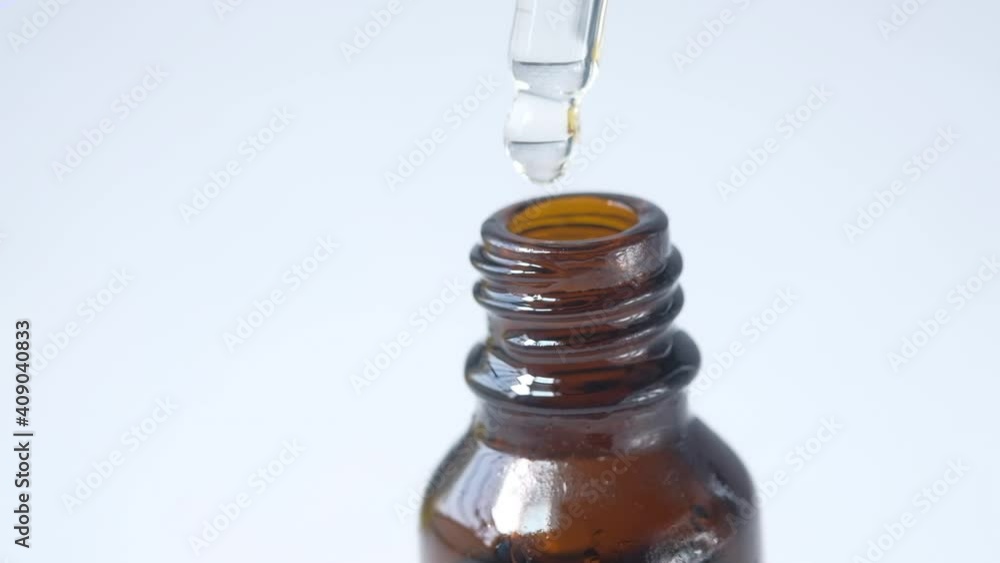 Drop falls from a pipette into a cosmetic bottle Drop falls from a pipette into a cosmetic bottle