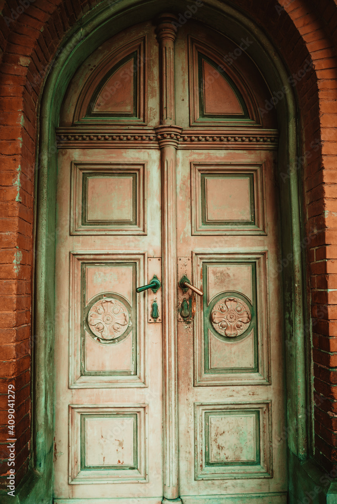 vintage antique doors of ancient building with erased green and pink paint