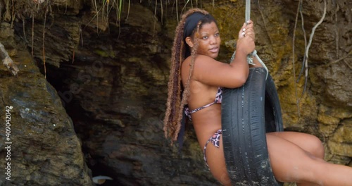 A girl with long braided hair enjoying a tire swing at the beach photo
