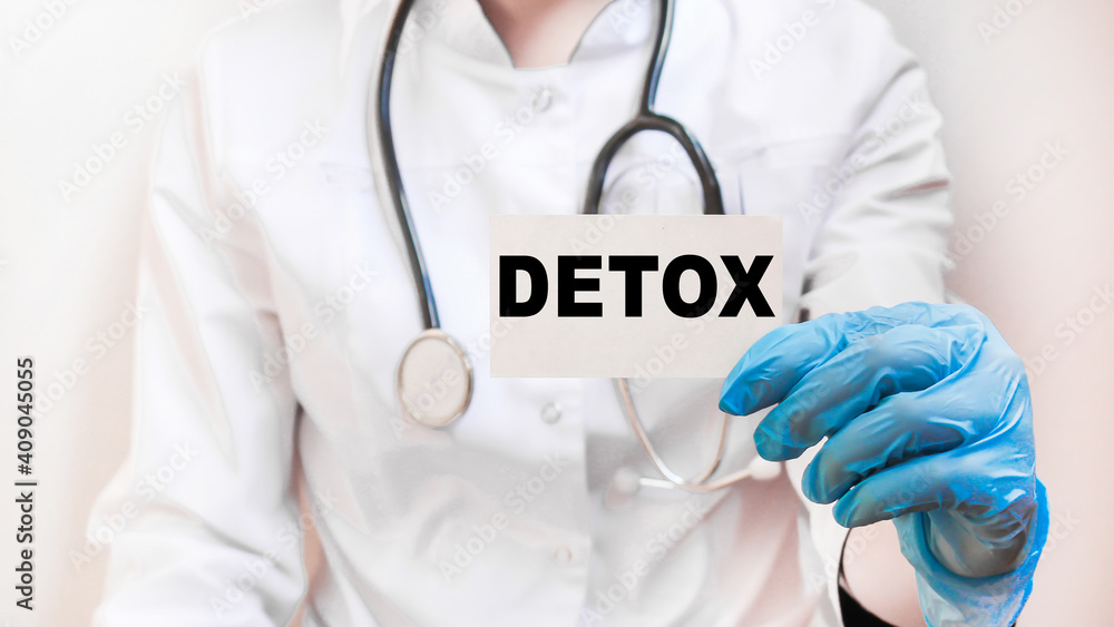 The doctor's blue - gloved hands show the word DETOX - . a gloved hand on a white background. Medical concept. the medicine