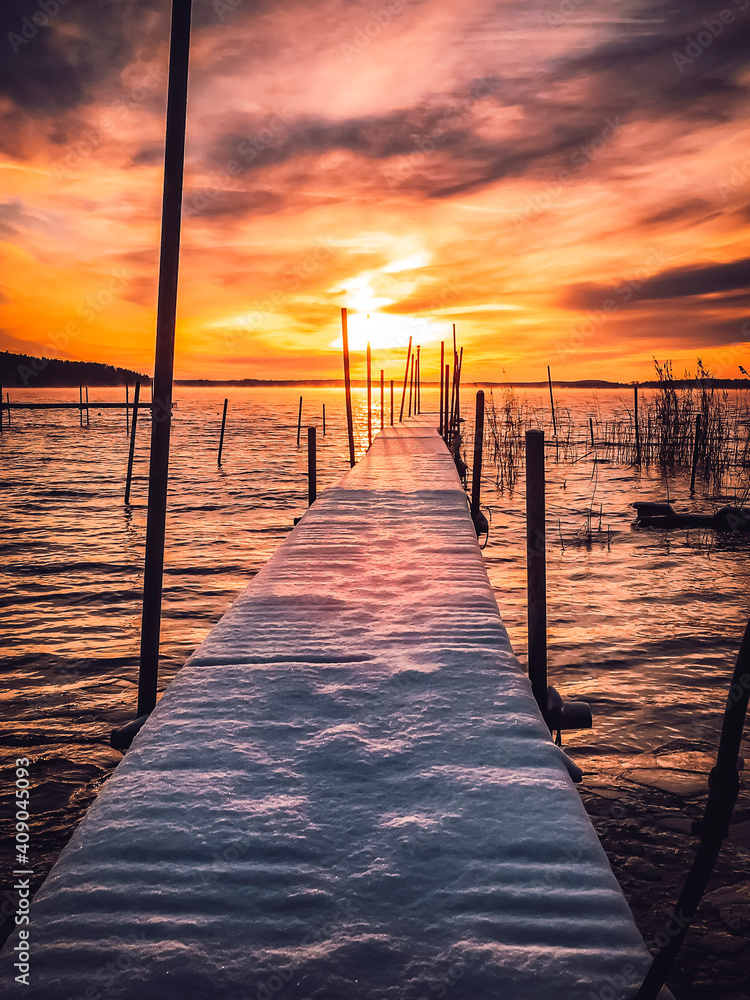 sunset on the pier with snow in it, during winter in the evening