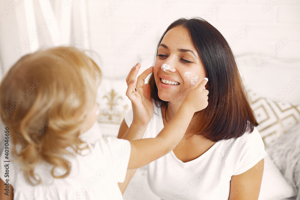Beautiful woman with child. Woman in a white t-shirt. Mother with doughter using a cosmetics.