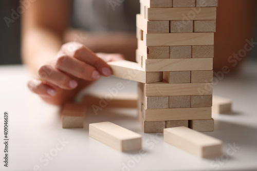 Female hand taking out block from wooden tower closeup
