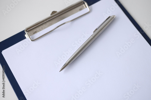 Ballpoint pen lying on clipboard with blank document closeup
