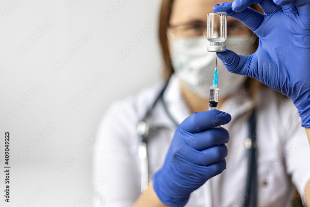 A female doctor wearing a medical mask draws the coronavirus vaccine into a syringe at the clinic.The concept of vaccination, immunization, prevention against Covid-19. A female doctor wearing a medical mask draws the coronavirus vaccine into a syringe at the clinic.The concept of vaccination, immunization, prevention against Covid-19.