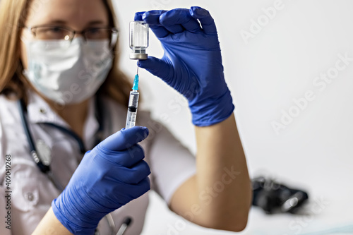 A female doctor wearing a medical mask draws the coronavirus vaccine into a syringe at the clinic.The concept of vaccination, immunization, prevention against Covid-19.