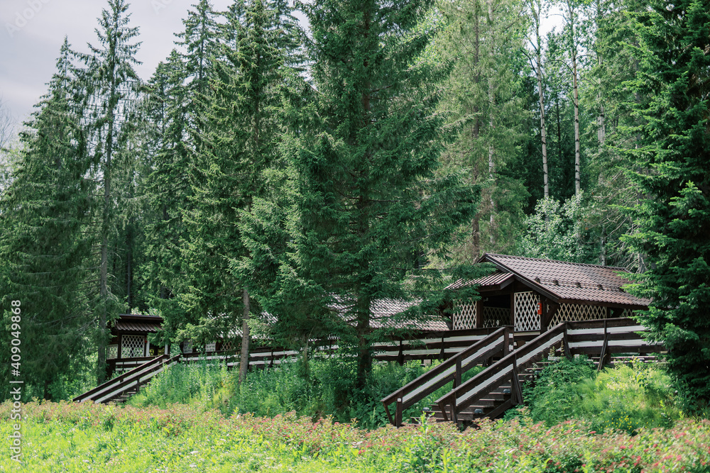 Wooden buildings of the recreation center. Ladders, fences and campsites in the middle of deciduous and coniferous forest. Rest outside the city with hunting and fishing.