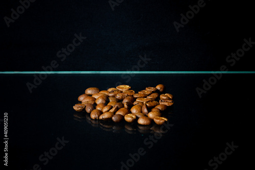 Roasted coffee beans on the glass surface, black background