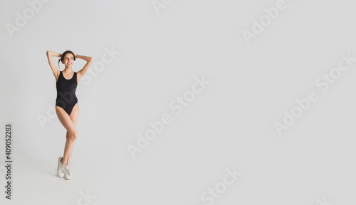 Tender. Beautiful young woman's isolated on white studio background. Having fun, happy, full length. Dancing, getting crazy mood, stylish posing. Fit girl in black sportive swimsuit. Flyer.