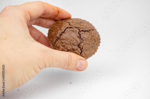 Homemade chocolate brown muffins in a hand. isolated on white background