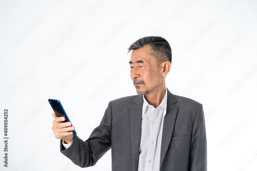 Happy Senior old Asian businessman in grey suit texting and uses the social network on a cell phone. And online Shopping, online technology for the active elder concept. Over white background Happy Senior old Asian businessman in grey suit texting and uses the social network on a cell phone. And online Shopping, online technology for the active elder concept. Over white background