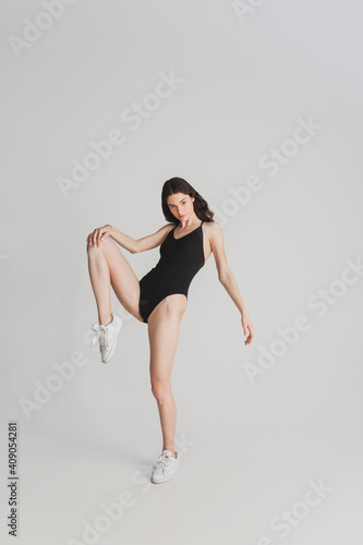 Freedom. Beautiful young woman's isolated on white studio background. Having fun, happy, full length. Dancing, getting crazy mood, stylish posing. Fit girl in black sportive swimsuit. Copyspace.