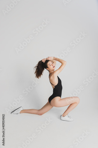 Flexible. Beautiful young woman's isolated on white studio background. Having fun, happy, full length. Dancing, getting crazy mood, stylish posing. Fit girl in black sportive swimsuit. Copyspace.