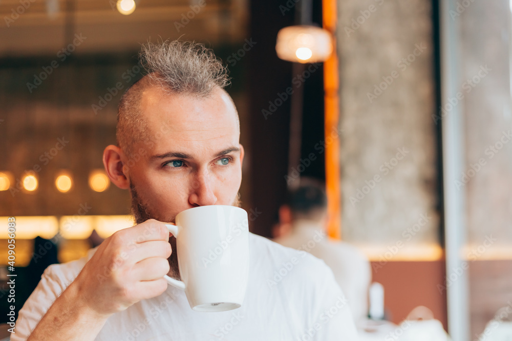Brutal man of European appearance in a cafe in the morning with a cup of hot coffee Brutal man of European appearance in a cafe in the morning with a cup of hot coffee