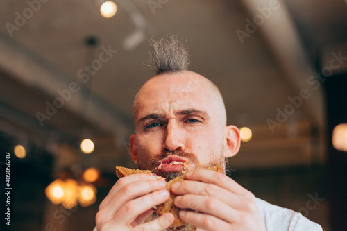 A brutal man of European appearance in a cafe has a delicious sandwich