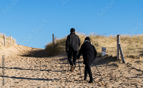 Vendée, France; January 25, 2021: A couple of Nordic walkers enjoying the good weather come back from the beach, Bretignolles Sur Mer.
