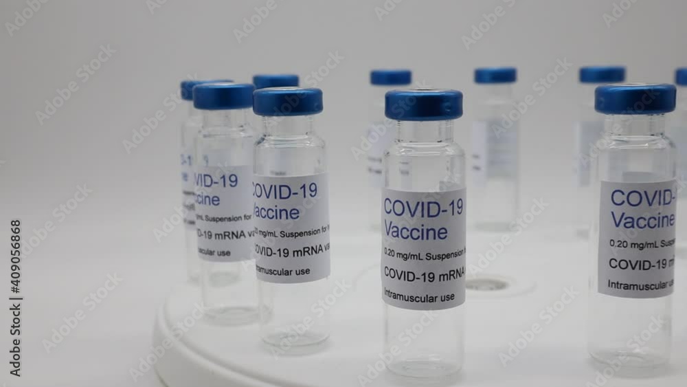 Transparent empty glass vials with Covid-19 Vaccine label on rotating display. Close-up Transparent empty glass vials with Covid-19 Vaccine label on rotating display. Close-up
