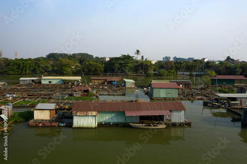 Iron buildings and infrastructure in floating fish farming community in Bien Hoa on the Dong Nai river, Vietnam on a sunny day © Paul