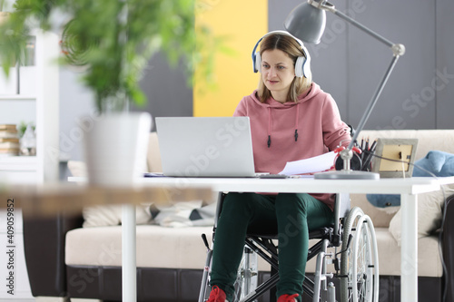 Young woman in wheelchair working on laptop at home