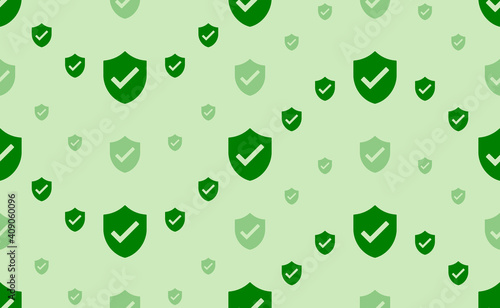 Seamless pattern of large and small green protection mark symbols. The elements are arranged in a wavy. Vector illustration on light green background