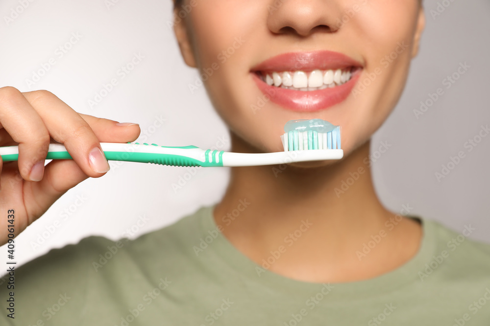 Woman holding toothbrush with paste on light background, closeup Woman holding toothbrush with paste on light background, closeup