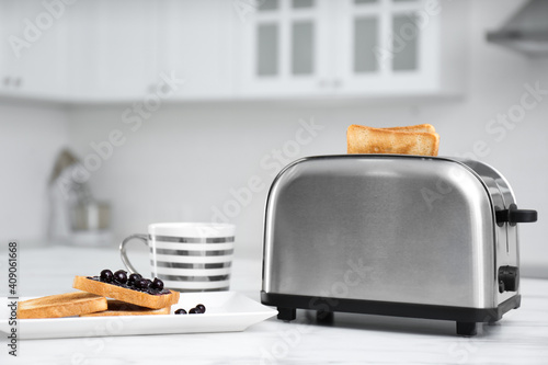 Modern toaster and tasty breakfast on white table in kitchen