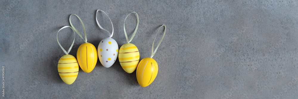 Banner copyspace. Easter colorful yellow eggs in a row with ribbons on the grey background with copy space. Flat lay. Top view - obrazy, fototapety, plakaty 