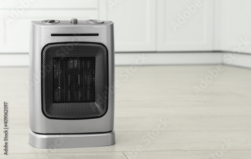 Modern electric fan heater on floor in kitchen. Space for text