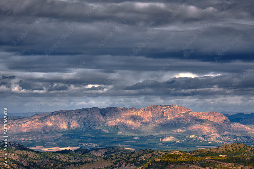 Fototapeta premium Dramatic and stormy sky over the mountains generating lights and shadows all over the horizon