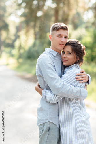 Cheerful young woman and man are hugging outdoors in summer park. couple in love having date and romantic vacation on sunny day. Love and relationships between young people