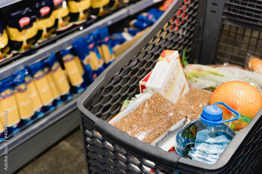 Package with buckwheat and bottle of water in shopping cart in supermarket Package with buckwheat and bottle of water in shopping cart in supermarket