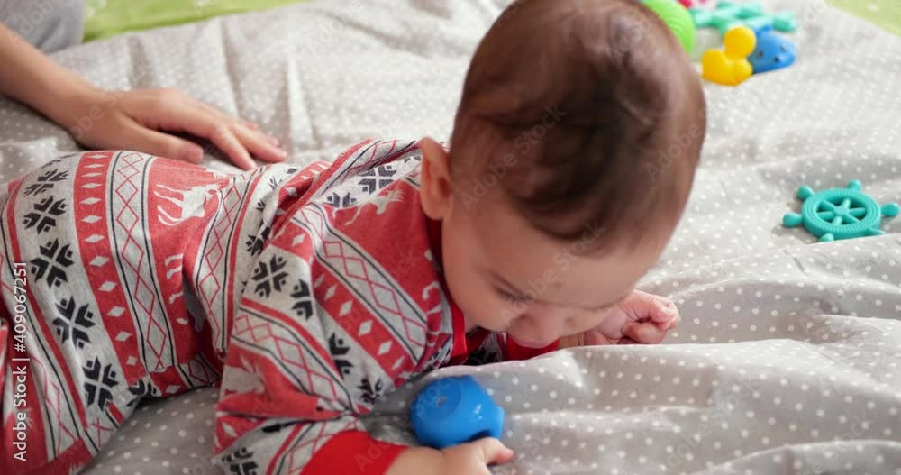 Happy Mother Lifting Baby Helps Son Sit Down Lying on Bed at Home. Mom teaches the Little boy to sit down. Mom and Little Child Playing at Home Happy Mother Lifting Baby Helps Son Sit Down Lying on Bed at Home. Mom teaches the Little boy to sit down. Mom and Little Child Playing at Home