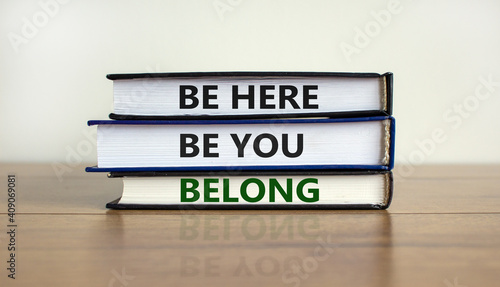 Belong symbol. Books with words 'be here, be you, belong' on beautiful wooden table, white background. Business, belonging and inclusion concept. Copy space.