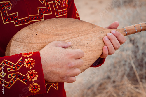 a guy in a red coat holding a dutar photo